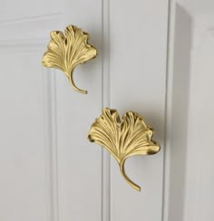 two gold leaf shaped hooks on a white door