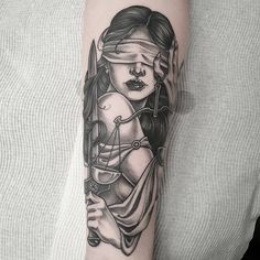 a woman with a blindfolded face holding an hourglass tattoo on her arm