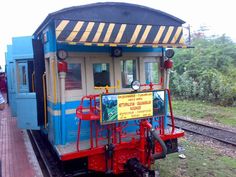 a blue and white train stopped on the tracks next to a man in a red shirt