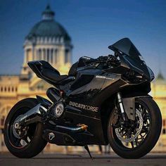 a black motorcycle parked in front of a large building with a dome on it's roof