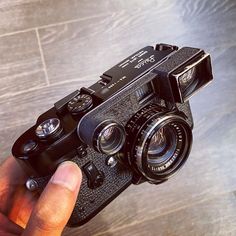 a person holding a camera on top of a wooden floor