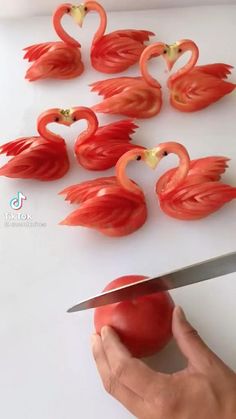 a person holding a knife and cutting tomatoes into flamingos