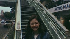 a woman is smiling while standing at the bottom of an escalator