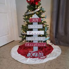 a small christmas tree decorated with wooden signs and lights in the shape of a house