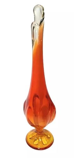 an orange glass vase sitting on top of a yellow base