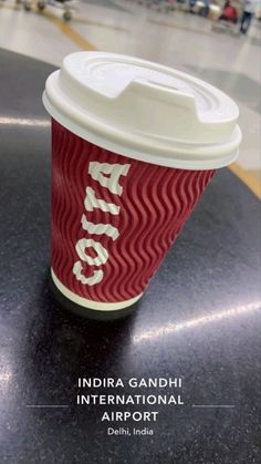 a red coffee cup sitting on top of a table next to a black countertop