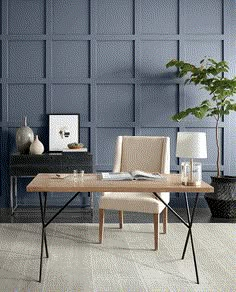 a dining room table with two chairs and a vase on it, next to a plant