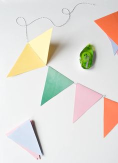 a string of colored paper hanging from a white wall next to a green tape measure