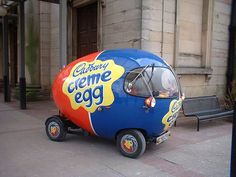 an egg shaped vehicle is parked on the sidewalk