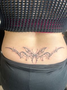 a woman's stomach with a butterfly tattoo on her lower back and side ribs