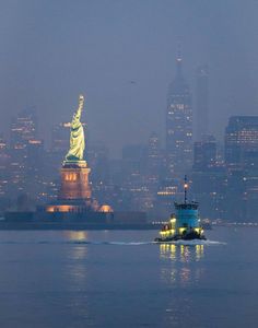 the statue of liberty is lit up at night in new york city's skyline