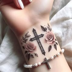 a woman's wrist tattoo with roses and a cross on the left side of her arm