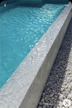 a pool with rocks and water next to the side walk that leads up to it