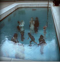 several people are standing in the water near a swimming pool