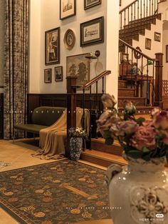 a living room filled with lots of furniture and pictures on the wall next to a stair case