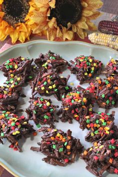 there are chocolate treats on the plate with sprinkles and corn in the background