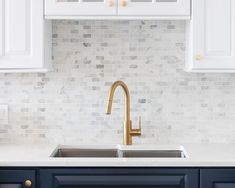 a kitchen with white cabinets and gold faucet in the middle of the counter