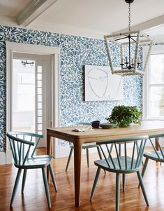 a dining room with blue and white wallpaper, wood flooring and wooden chairs