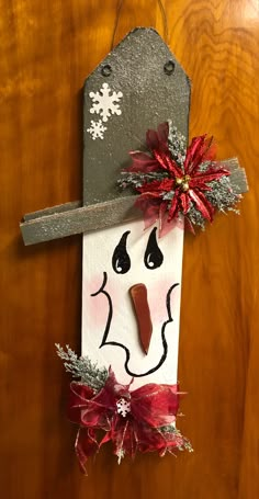 a snowman door hanger decorated with red and silver decorations on a wooden door