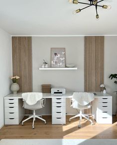 two white desks and chairs in a room with wood flooring on the walls