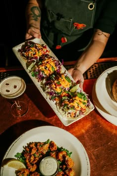 a person holding a plate with food on top of it next to other plates and glasses