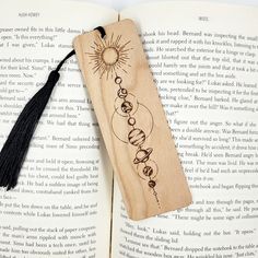 an open book with a wooden bookmark and tassel hanging from it's side