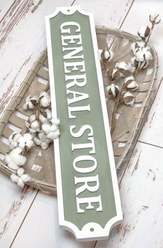 a sign that says general store next to some cotton on a table with white wood planks