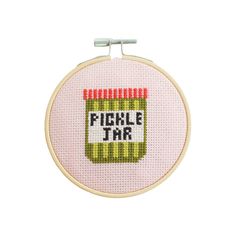 a cross - stitch hoop with the words pickle jar on it, and a needle in