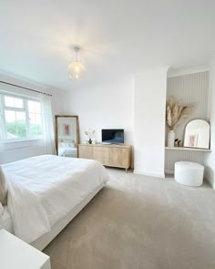 a bedroom with a bed, dresser and television on the far side of the room