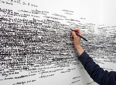 a man writing on a large wall with lots of words written all over the place