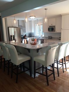 a kitchen with an island and bar stools in the center, surrounded by white cabinets