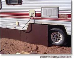 an rv is parked in the dirt with its door open and it's trailer plugged into the ground