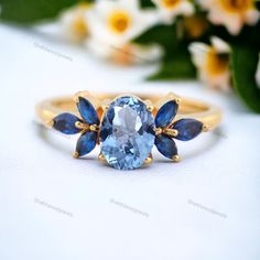 a ring with blue stones on it and flowers in the background