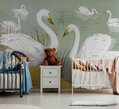 a baby's room with two swans painted on the wall and a crib