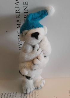 a stuffed polar bear with a blue hat on it's head and arms crossed