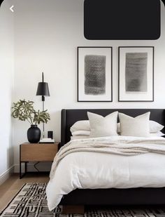 a bed with white sheets and pillows in a room next to two pictures on the wall