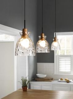 three pendant lights hanging from a kitchen ceiling