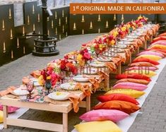 a long table is set up with orange and pink pillows