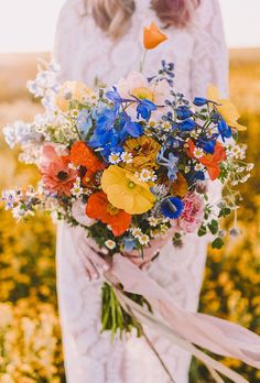 a woman in a white dress holding a bouquet of wildflowers and other flowers