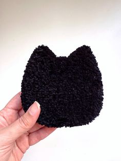 a hand holding a black cat shaped object