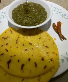 a plate with some food on it and a bowl filled with green sauce next to two tortillas