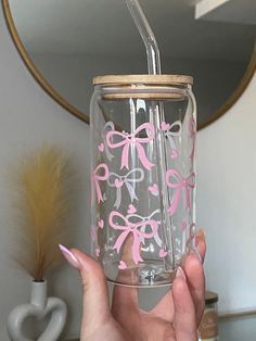 a person holding up a clear cup with pink bows on it