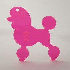 a pink poodle shaped object on a white surface with an orange tag in the middle