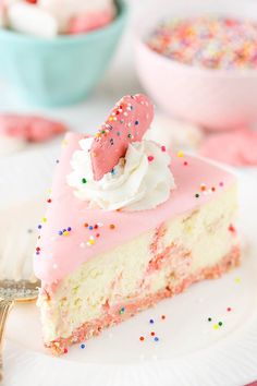 a piece of cake with pink frosting and sprinkles on a plate