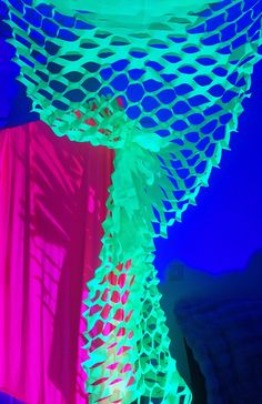 an artistic display with neon colors in the night sky and on top of it is a large net