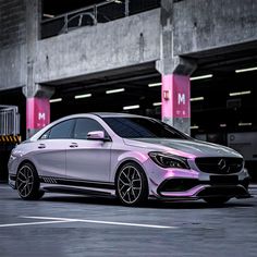 a white mercedes benz cla parked in a parking lot next to a pink building