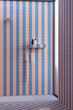 a bathroom with blue and pink tiles on the walls, shower head and shelf in the corner