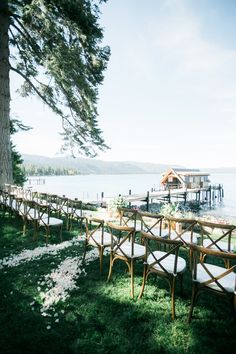 chairs and tables set up on the grass by the water