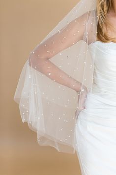 a woman in a white wedding dress with a veil on her head and one arm