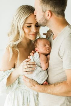 a man and woman holding a baby in their arms